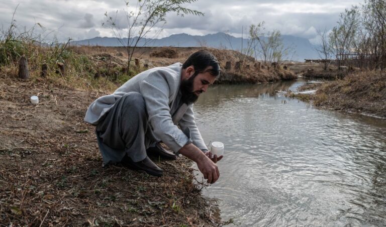 Man gathers water and soil samples at a water outflow